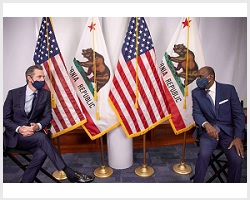 Gavin Newsom and Justice Martin Jenkins sitting socially distanced in front of California and American flags. 