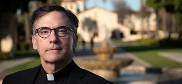 Portrait of Fr. Kevin O'Brien in front of the Mission.
