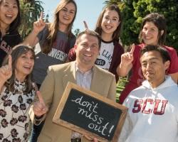 Alumni holding chalk board sign.