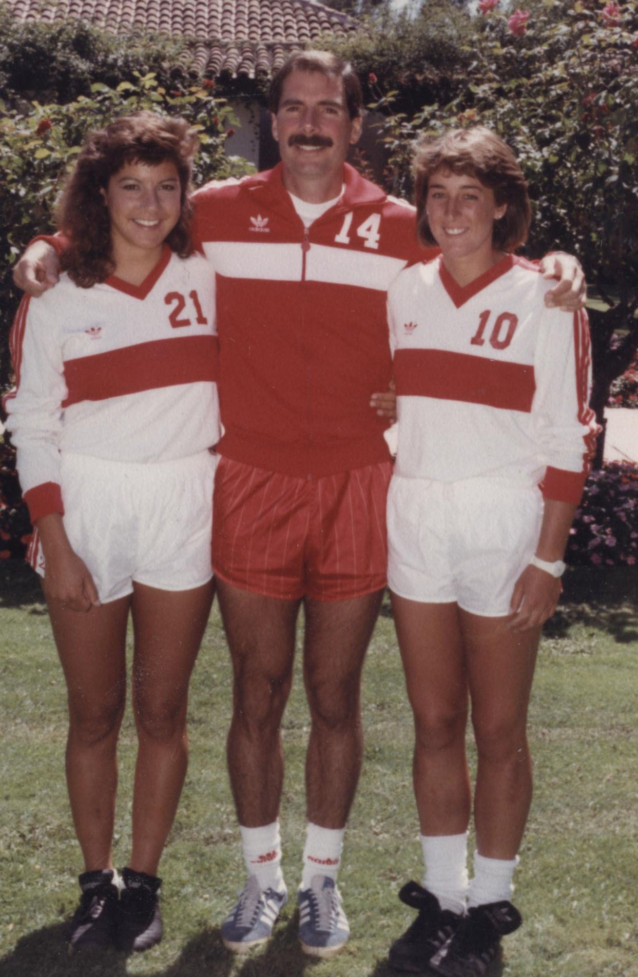 Three people in sports attire standing together on a field.