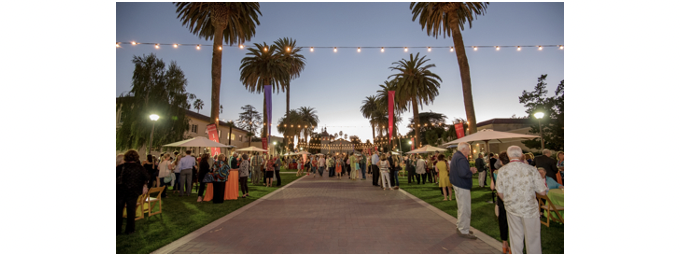 People enjoying a block party under palm trees at sunset.