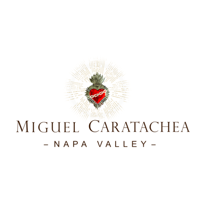 The words Miguel Caratachea Napa Valley sit below a red heart wrapped in thorns, encased by decorative metal, and surrounded by light waves. 