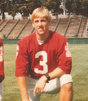 Athlete wearing a red football jersey with the number 3, kneeling on a football field.