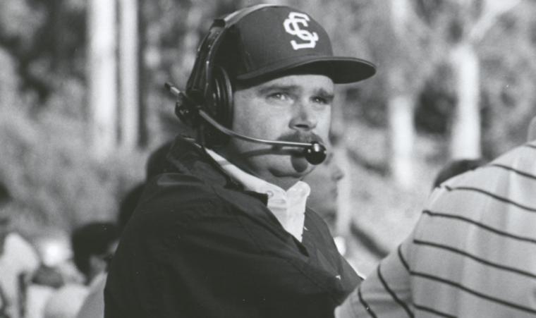 A man in a cap and headset during a sports event.
