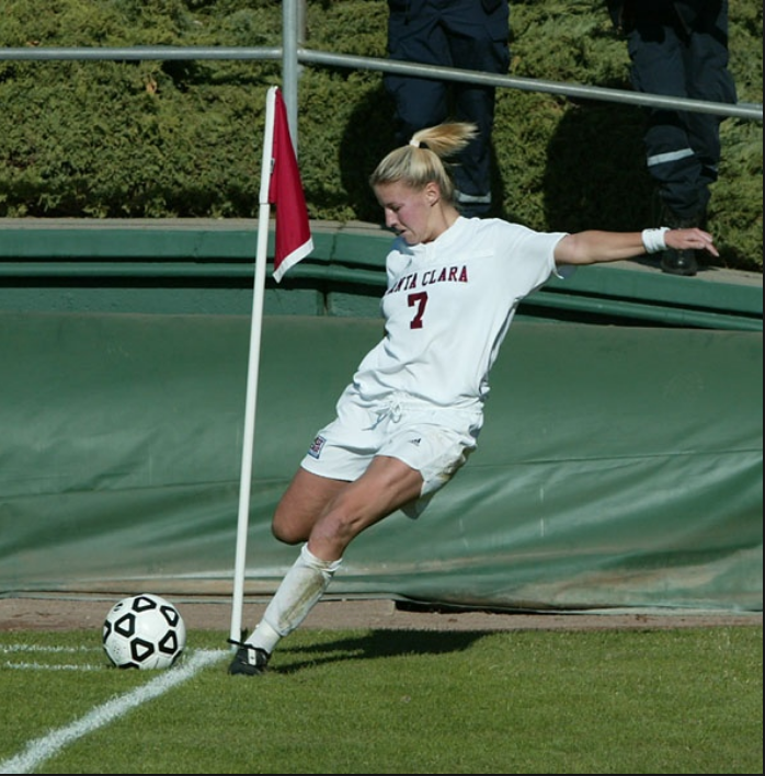 Soccer player in white uniform taking a corner kick.