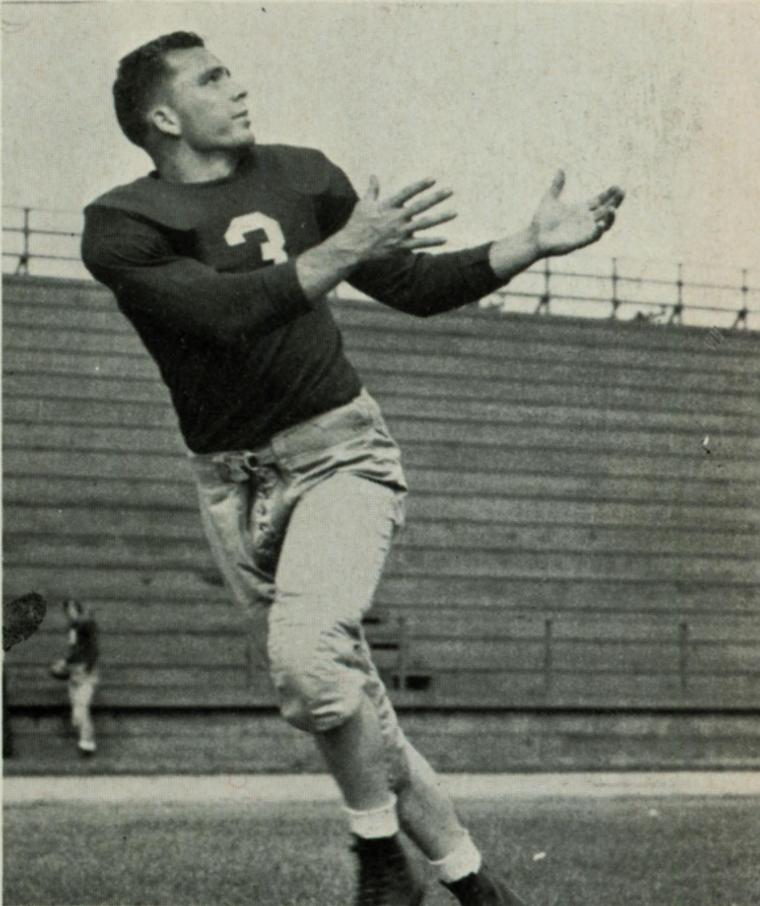 A football player in uniform catching a ball on a field.