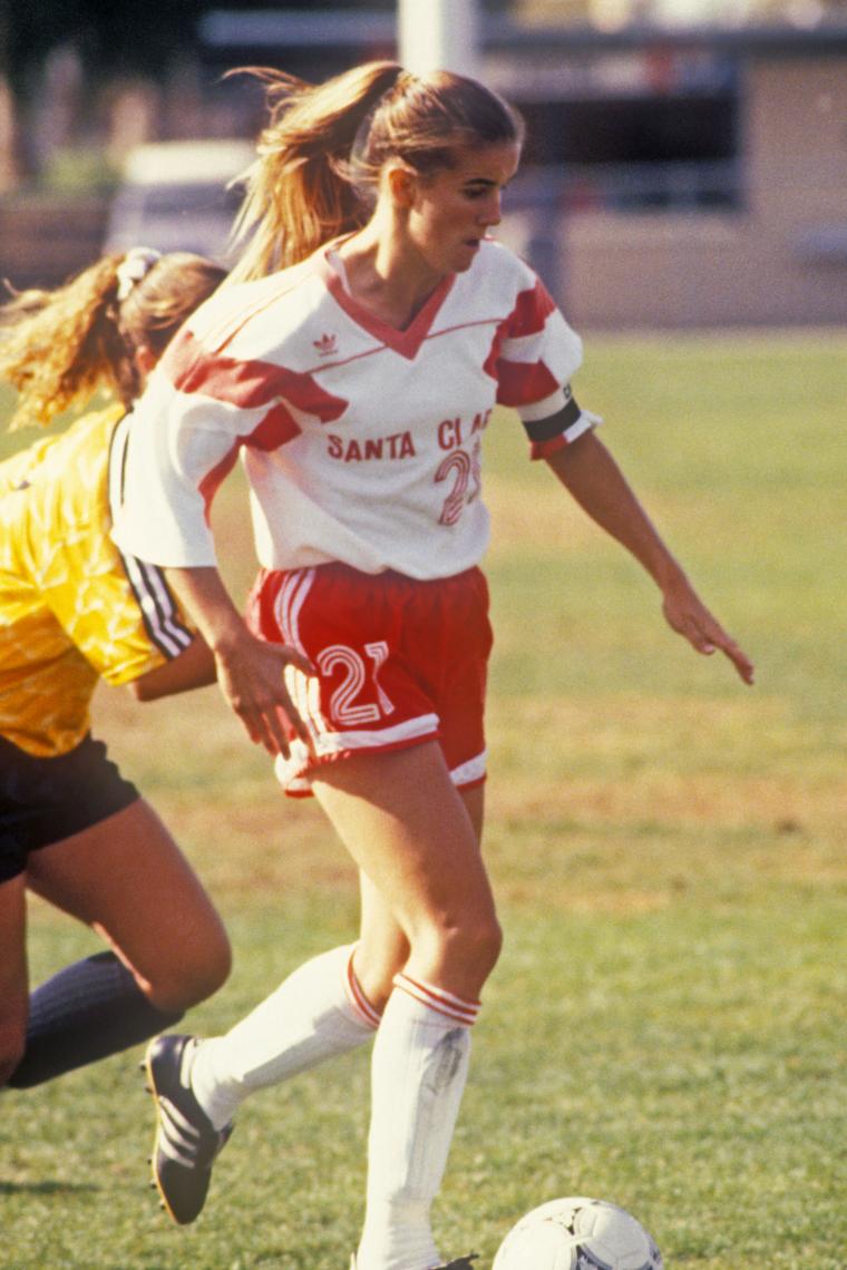 Soccer player in action on the field, opponent behind, ball at feet.