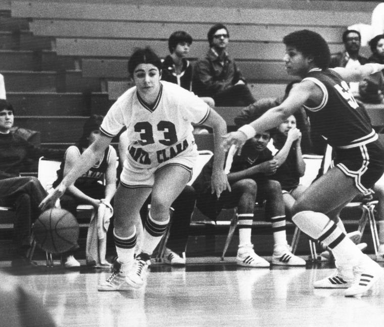 Basketball player dribbling past a defender in a game.