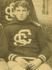 Sepia-toned photo of man in sweater with intertwined letters CS.