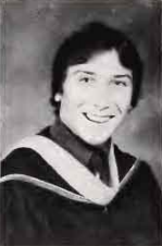 A grayscale portrait of a smiling person in a graduation gown.