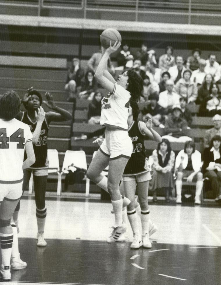 Black and white photo of a basketball game mid-jump shot.