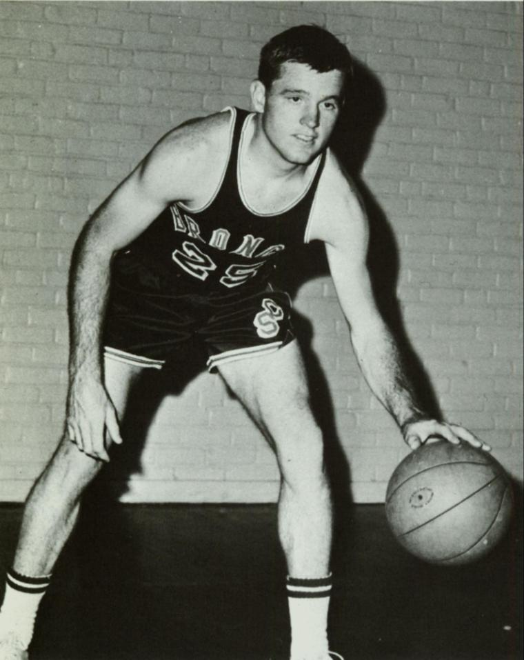 Black and white photo of a basketball player in a dribbling stance.