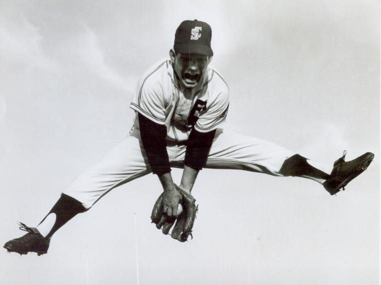 A baseball player jumping and catching a ball mid-air.