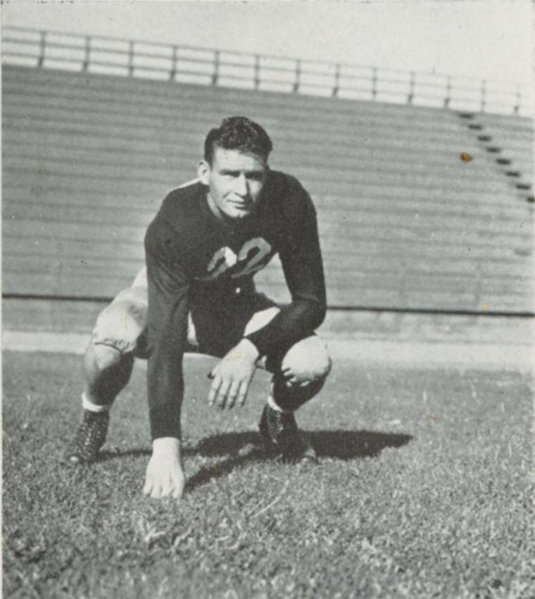 A black and white photo of a crouching football player.
