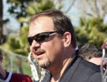 A man with sunglasses talking to people outside.