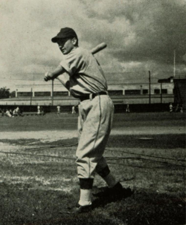 A baseball player in uniform prepares to swing a bat, 1942.
