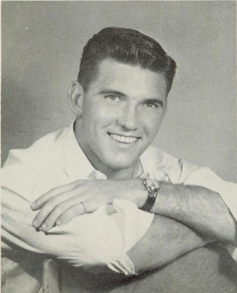 A smiling man leaning on his crossed arms.
