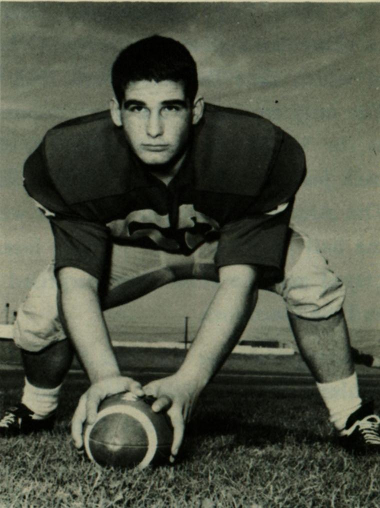 A football player in uniform ready to snap the ball.