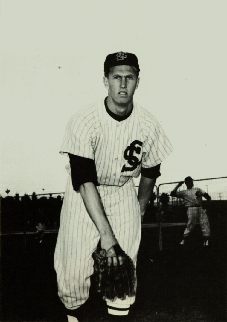 A baseball player in uniform holding a ball, preparing to pitch.