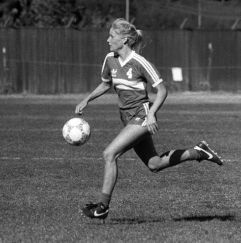 Black and white image of a soccer player in action, titled Jennifer Meek (Symons) HOF.