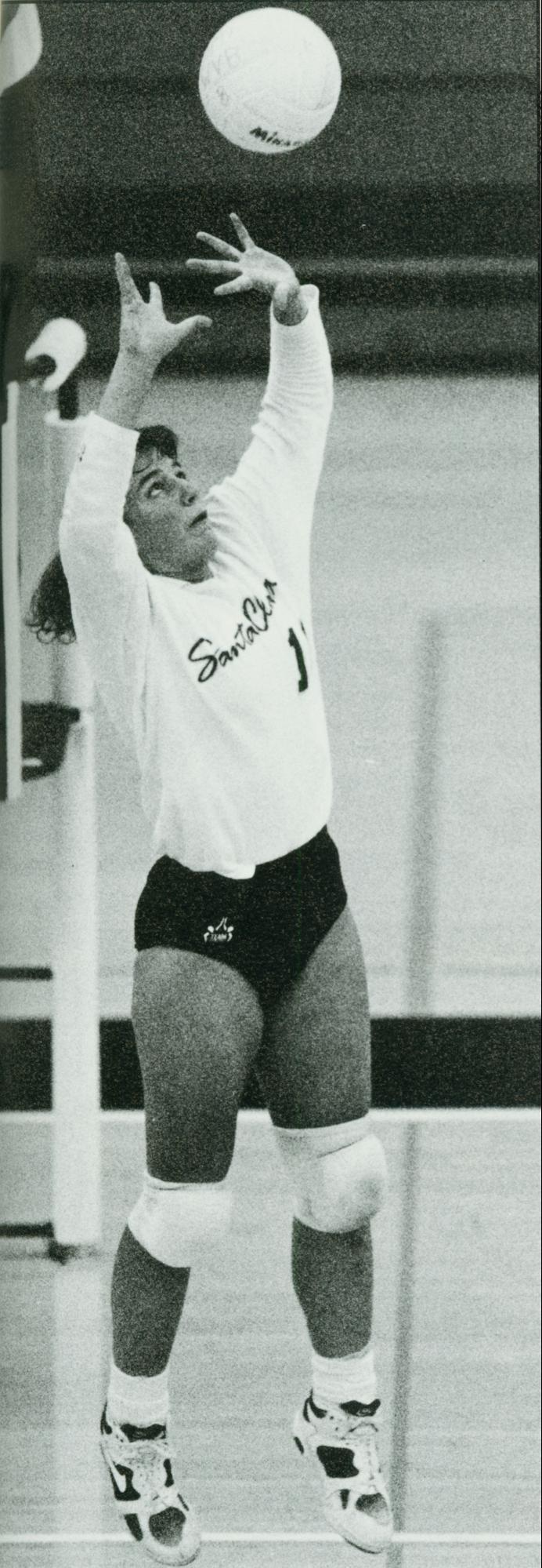 A volleyball player jumps to set a ball.