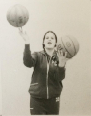 A woman balancing a basketball in each hand.