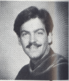 Black and white portrait of a smiling individual with a mustache.
