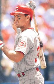 A baseball player with a bat, wearing a gray jersey and red helmet.