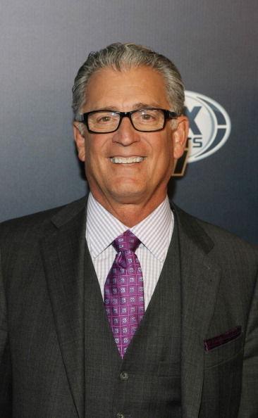 A man in a suit with glasses and a purple tie.