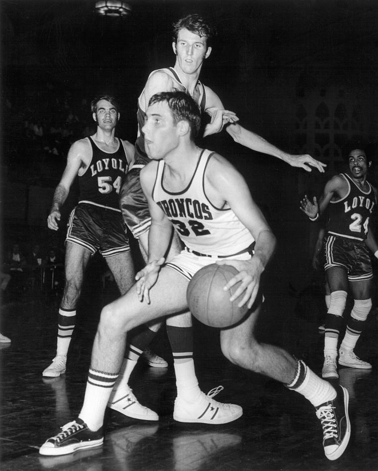 Black and white photo of basketball game with four players on the court.