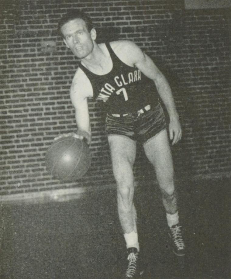 Black and white photo of basketball player in motion near a brick wall.