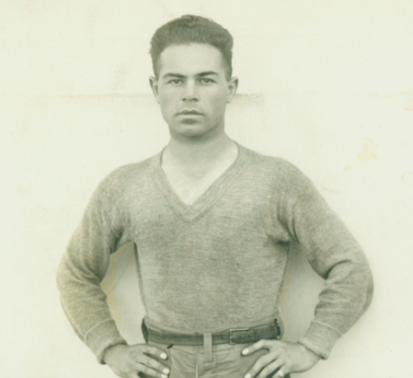 Man in a vintage sports uniform with hands on hips.