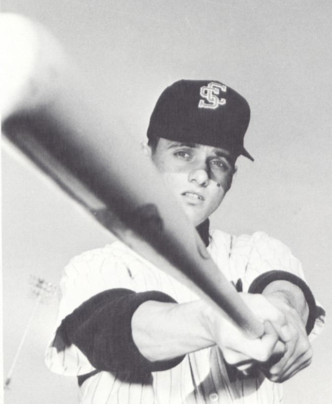 A baseball player aiming a bat at the camera.