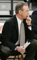 A man in a suit sitting, holding a paper.