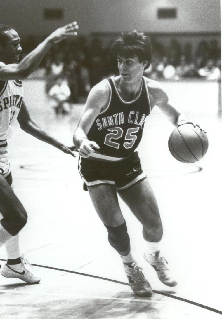 A basketball player dribbling while being guarded. Text: Class of 1986.