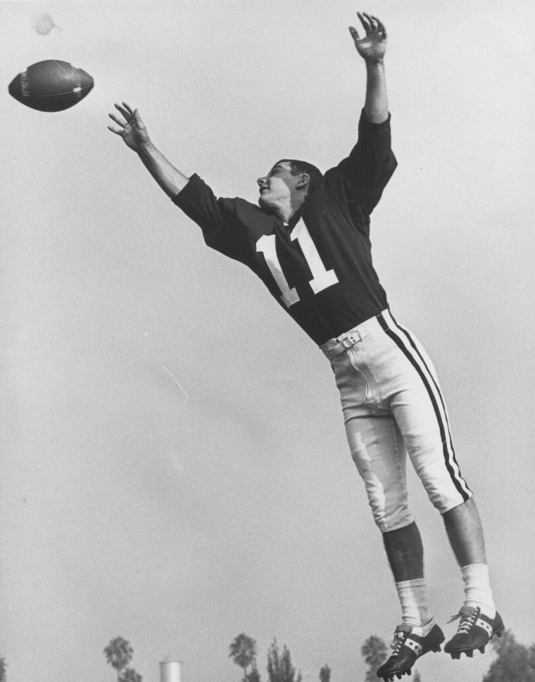 A football player jumping to catch a ball in mid-air.