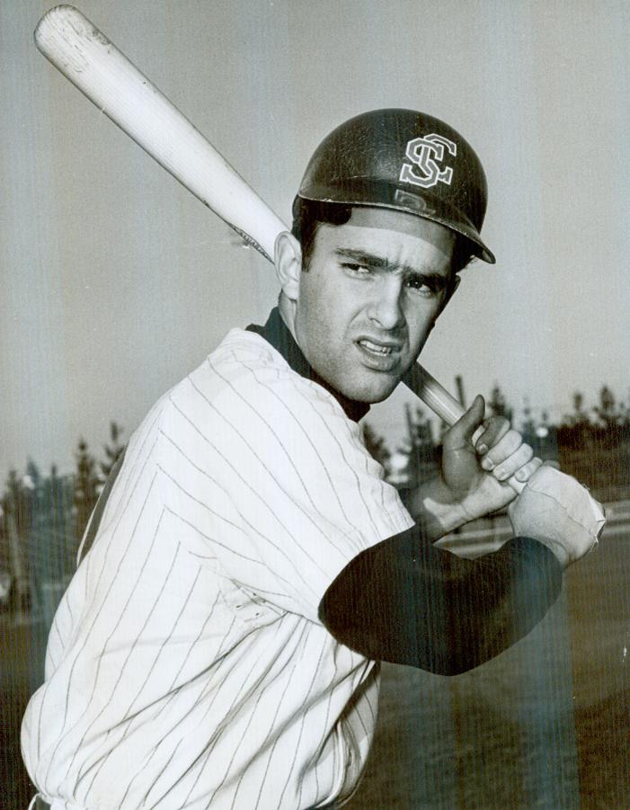 A black-and-white image of a baseball player holding a bat.