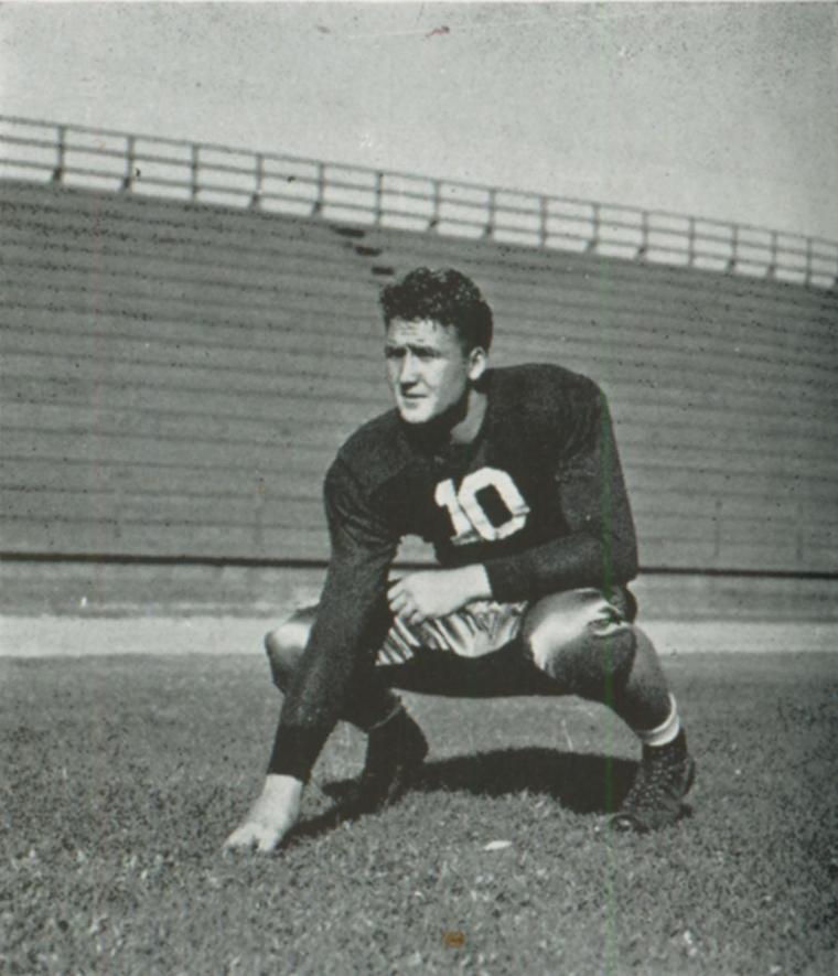 A football player in crouched position on a field wearing a number 20 jersey.