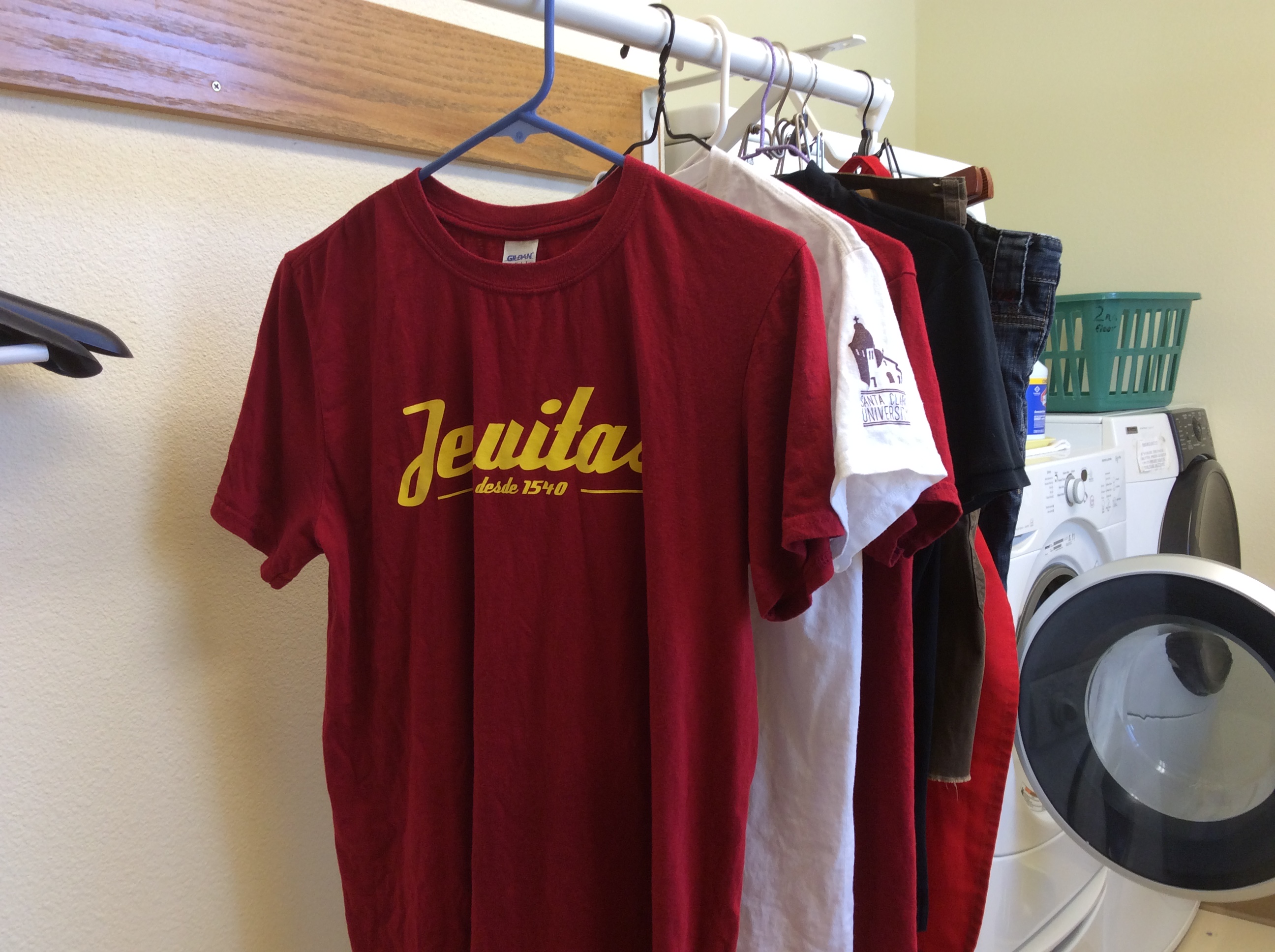 A row of hanging clothes, including a red shirt with yellow text. image link to story