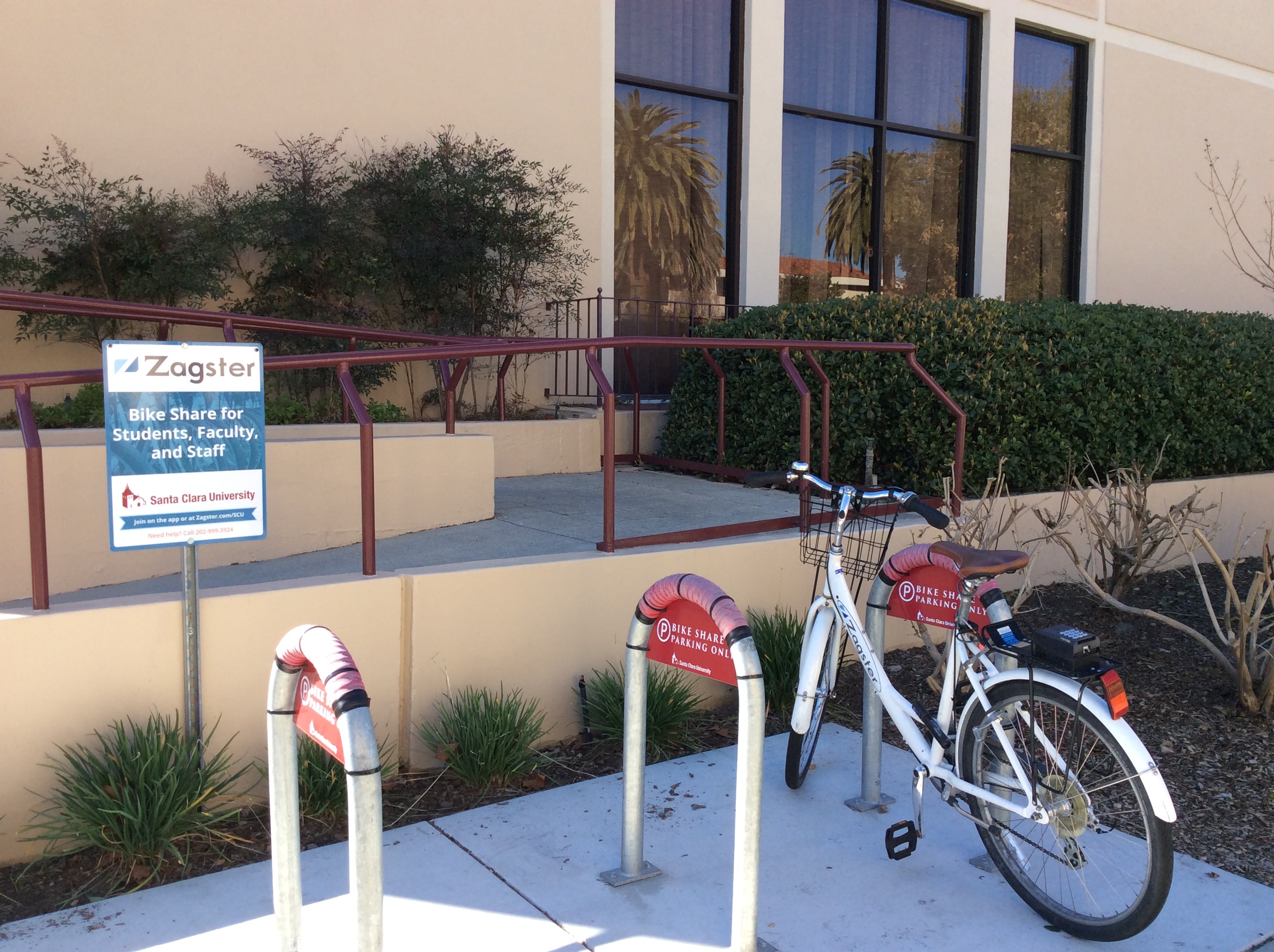 Two bikes parked at a bike rack outside a building. image link to story