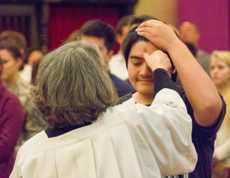 A person applying ashes to another person's forehead during Ash Wednesday.
