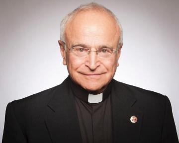 A man wearing clerical clothing and a pin, facing forward. image link to story