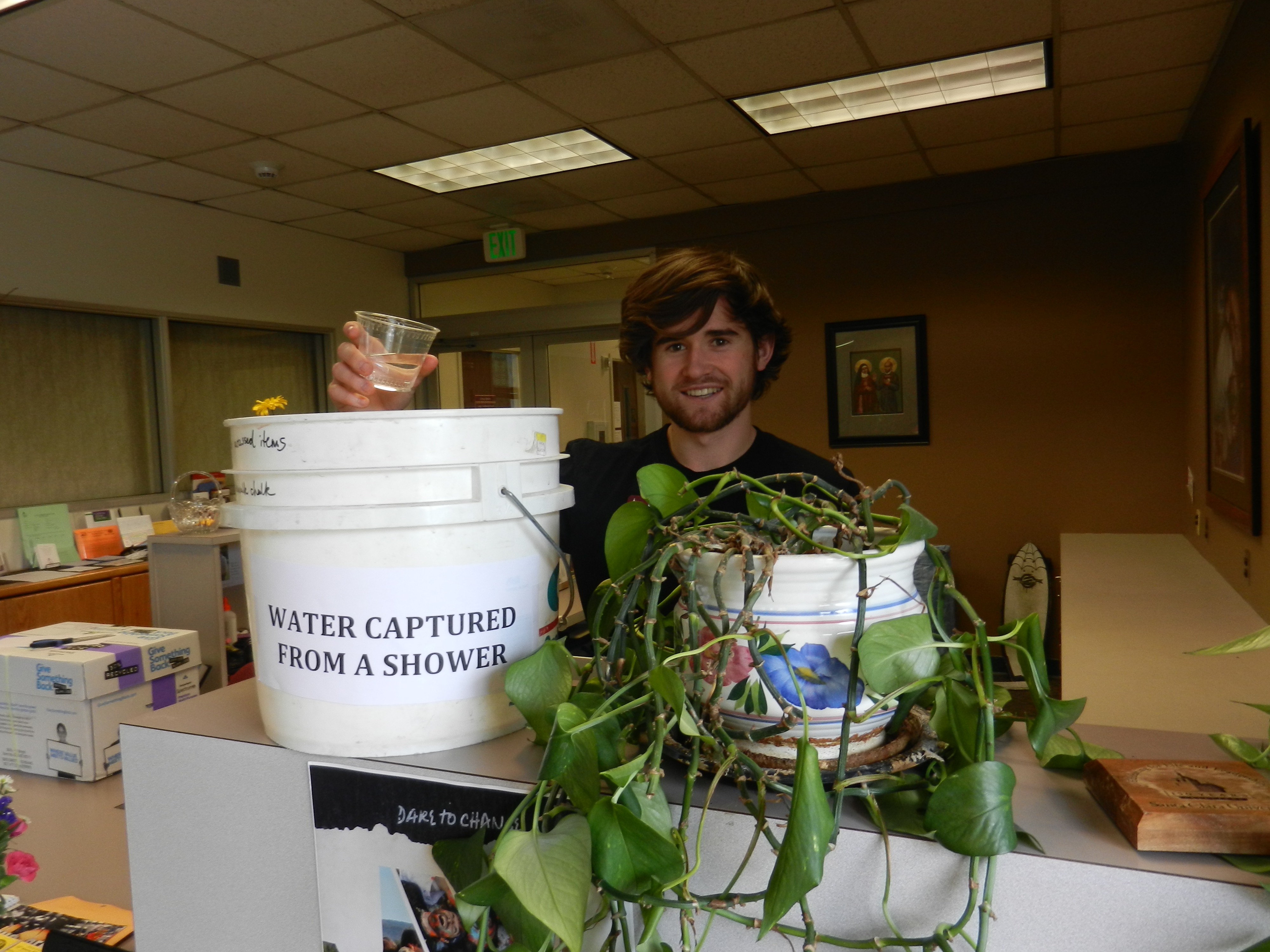 A person holding a white bucket near plants inside a room. image link to story