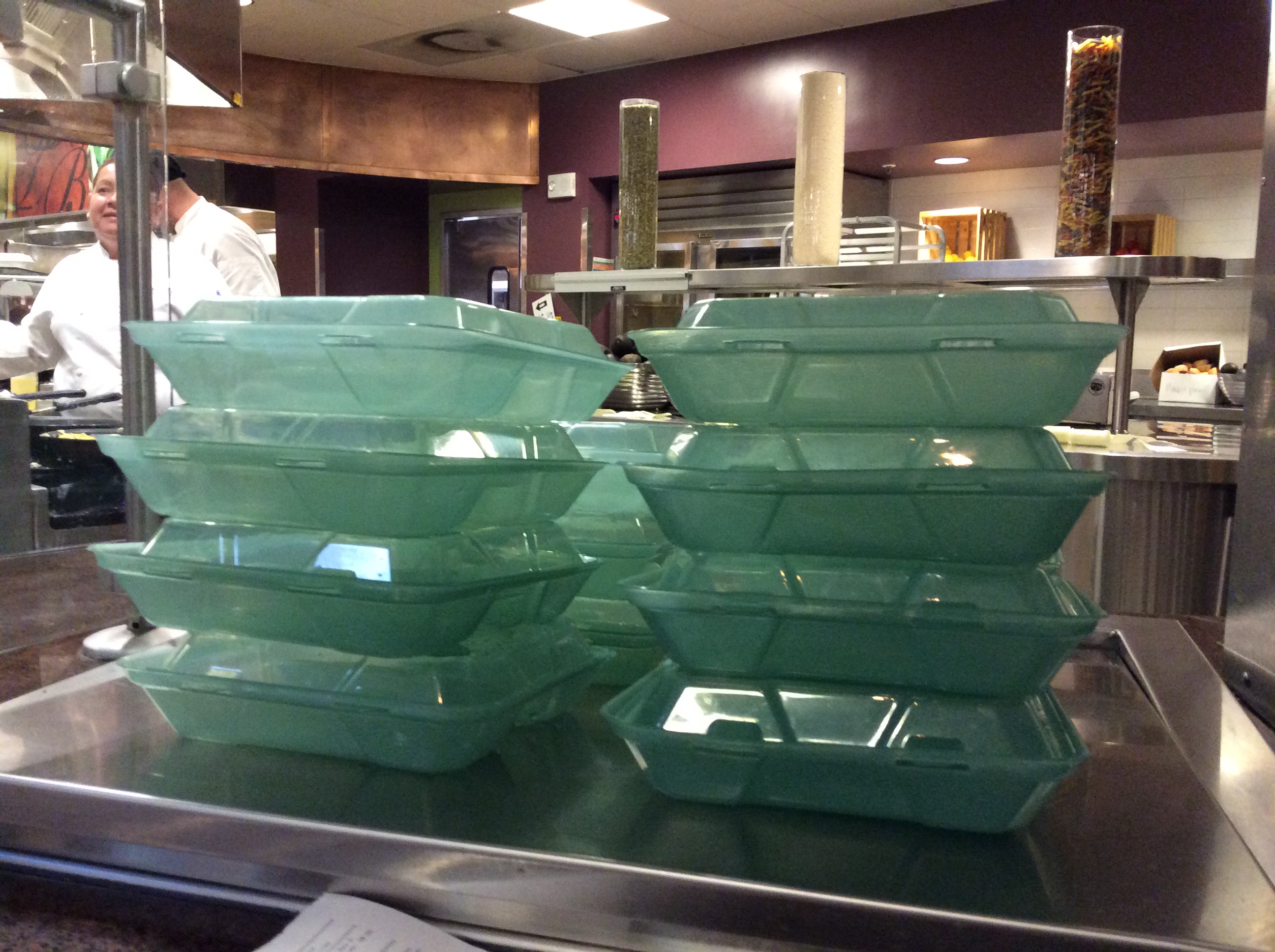 Stacked green eco-friendly trays at a cafeteria counter. image link to story