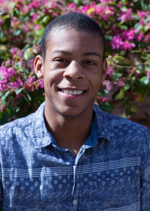 A man smiling in front of blooming flowers. image link to story