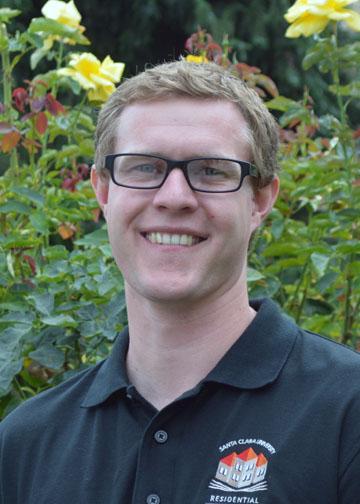 A person wearing glasses and a black shirt, outdoors with greenery in the background. image link to story