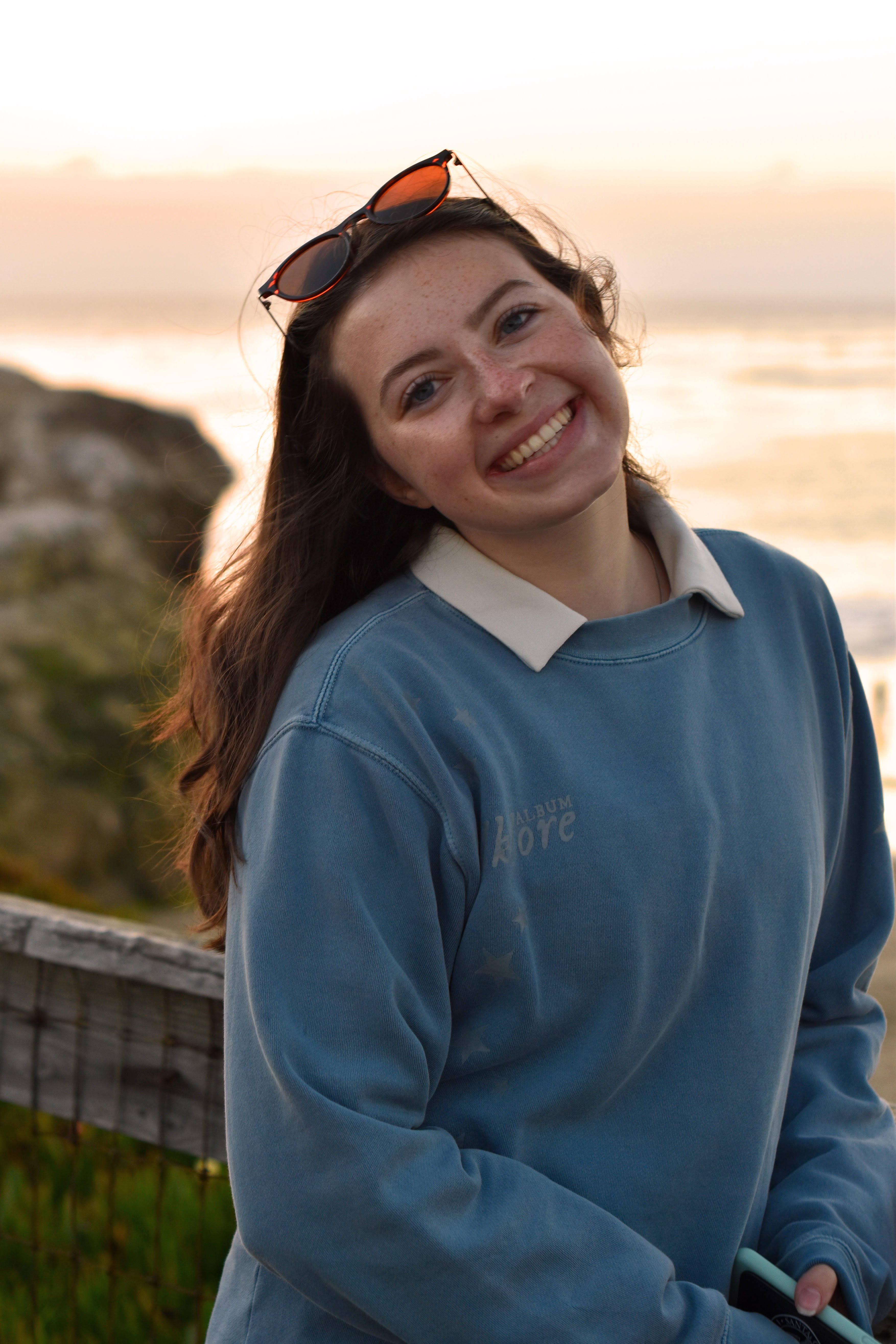 Caroline in blue sweater with sunset background