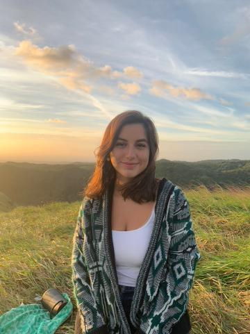 A person standing outdoors with a sunset in the background.