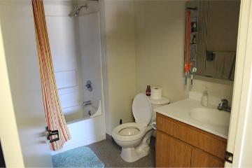 Bathroom with a bathtub, toilet, and a sink with a wooden cabinet.