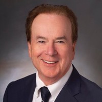 A man in a suit and tie, smiling.